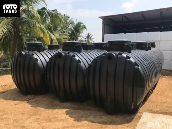 Large black plastic water storage tanks on dirt, manufactured by Rotomoulders in Kenya.